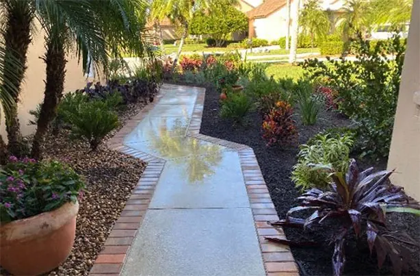 A widened front walkway bordered with pavers and new colorful planting