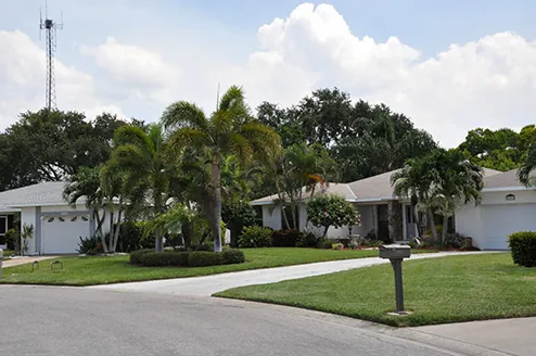 A Florida street of single-storey homes with mown verges and palms maintained by Greenscapes