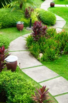 A winding stepping-stone path through planted beds, with glazed urns and low path lighting