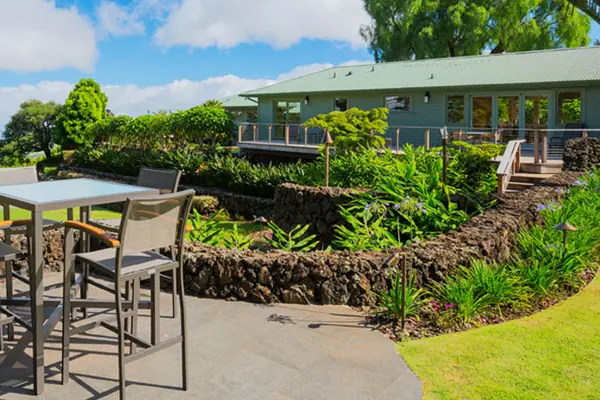 A paved terrace with seating beside a planted stone retaining wall and a building deck